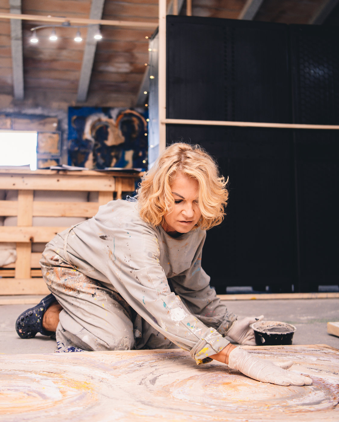 Karin Galler malt kniend auf einer Leinwand am Boden ihres Ateliers